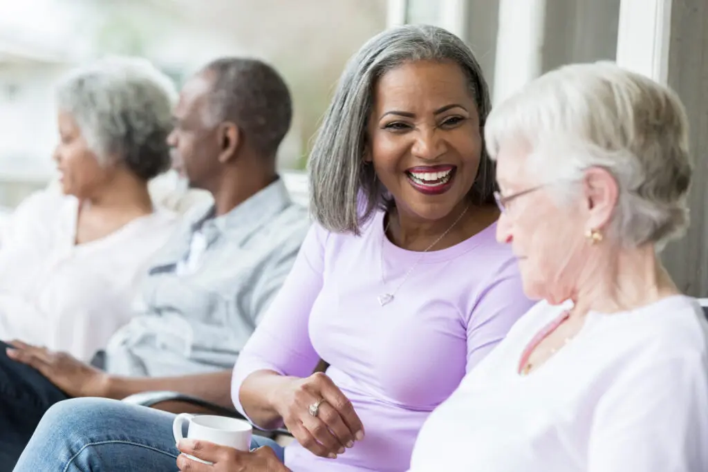 Senior woman enjoys conversation with friend on front porch