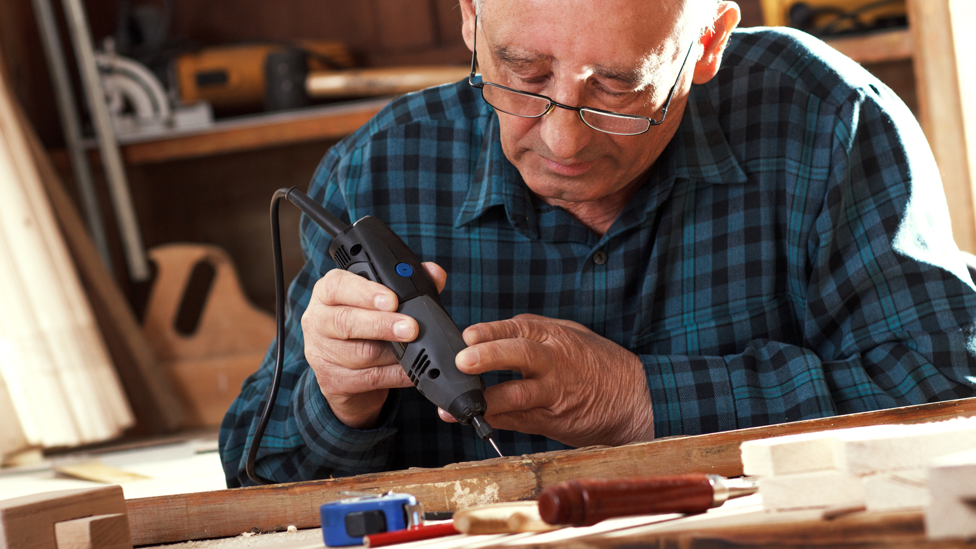 Senior carpenter carving wood with engraver tool. Restoring old furniture.