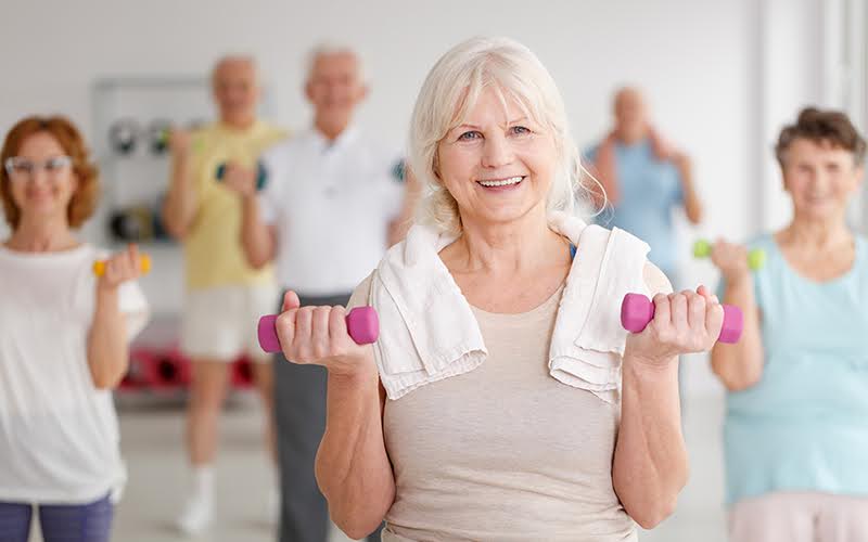 Active happy elders with colorful dumbbells during training