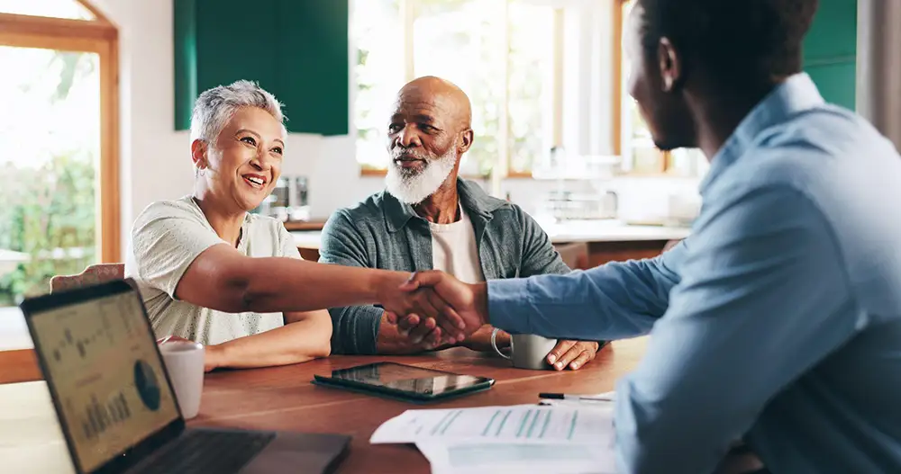 A senior couple shaking hands with an advisor during an estate planning for seniors consultation.